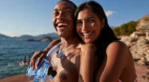 A couple smiling as they stand together with snorkelling equipment in their hands. (Generated with AI)