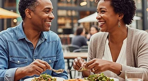 A couple is smiling at each other and enjoying food on a market. (Generated with AI)
