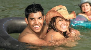 A couple swimming together in the water, smiling and having fun. (Generated with AI)