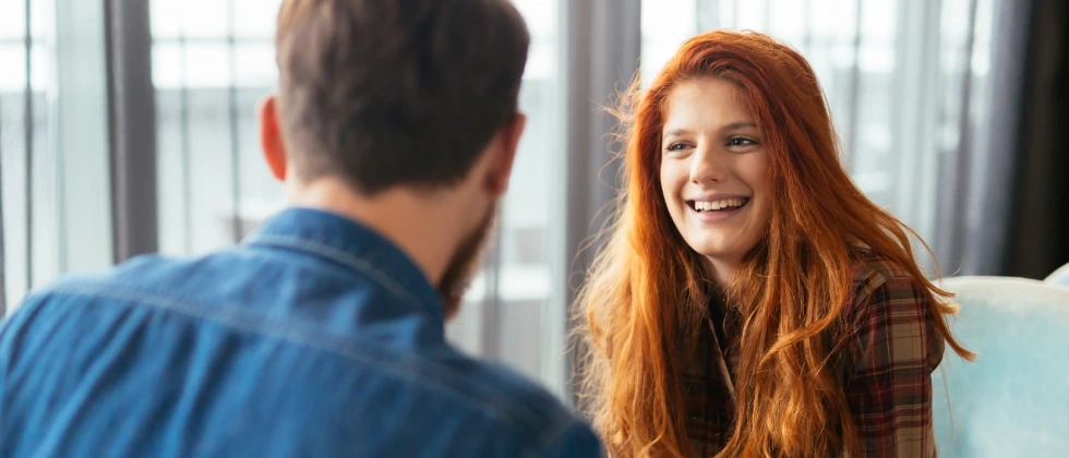 A women smiling and talking to a guy, showing how to ask a coworker out.