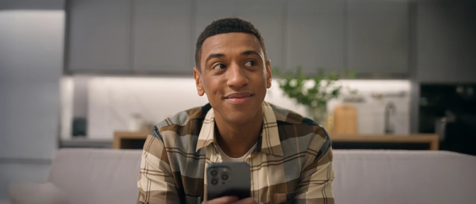 A man with his phone in his hands thinking about should I ask her out again.