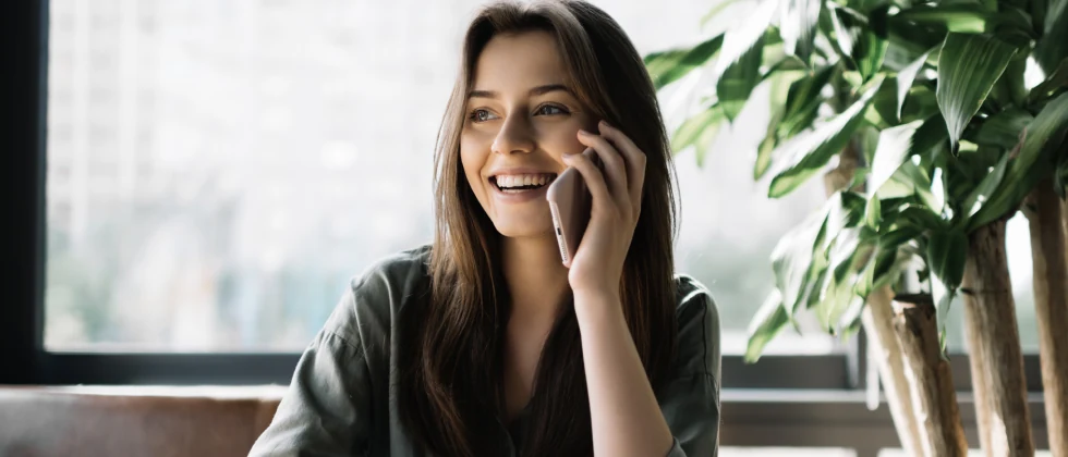 A woman smiles as she answers the phone.