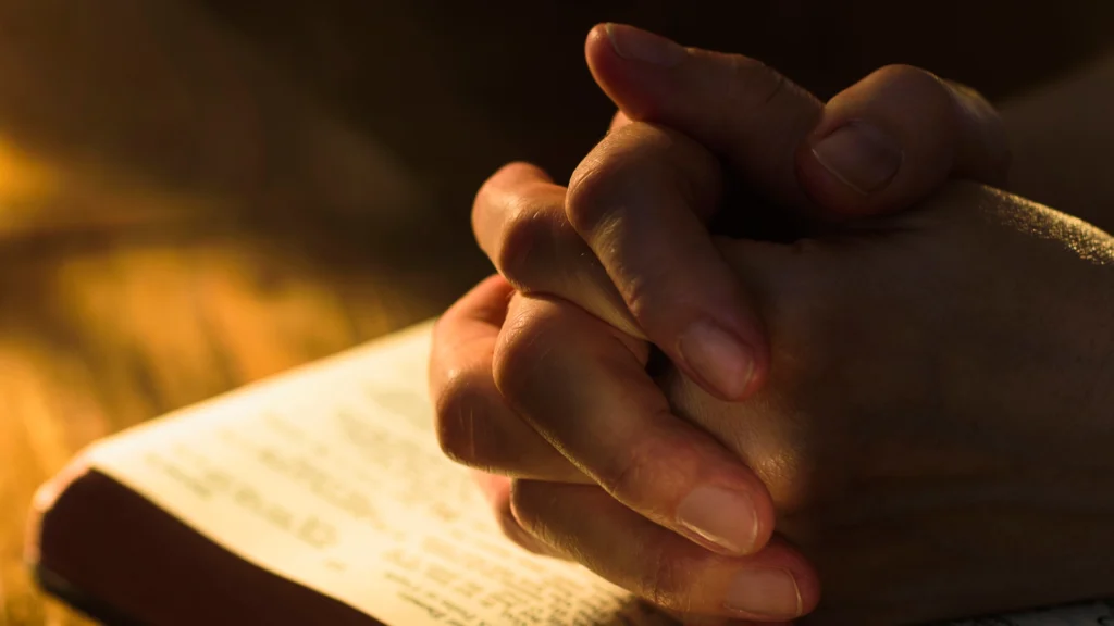 A hand is folded over a book.