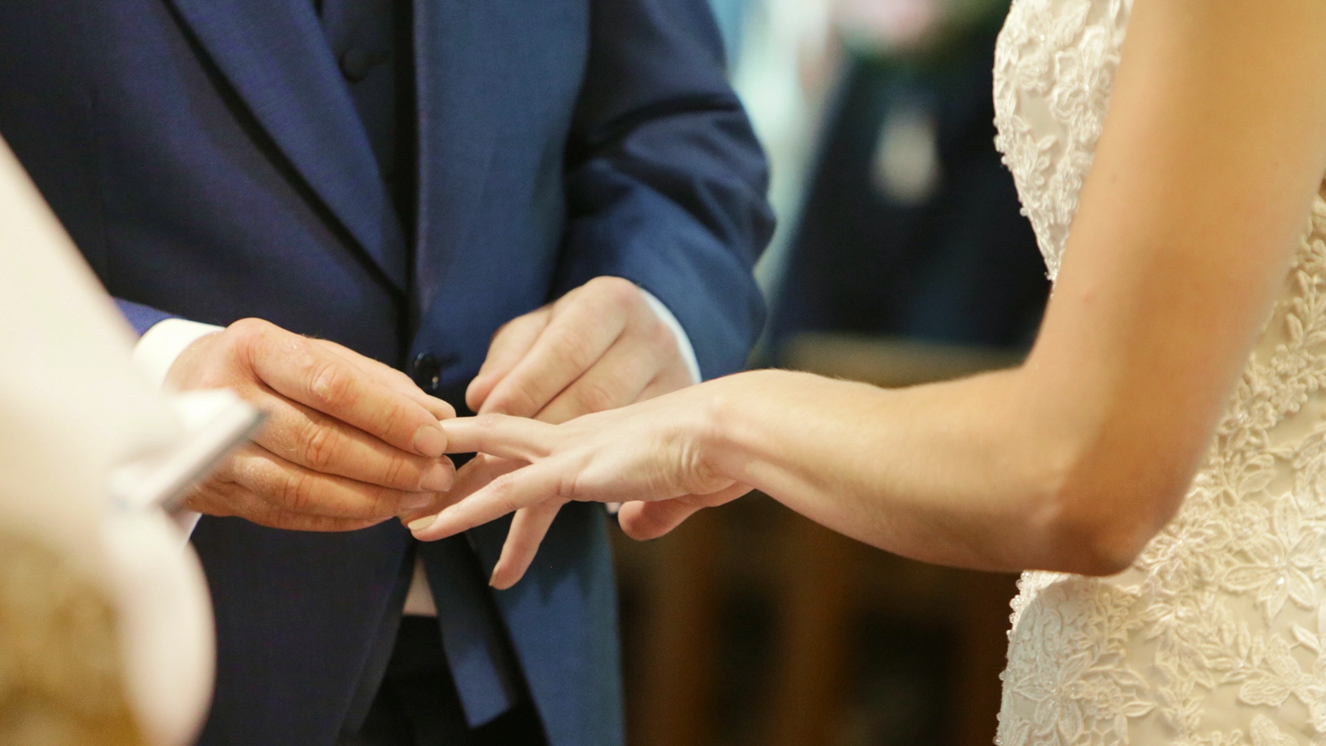 A man is putting a ring on his wife's finger.