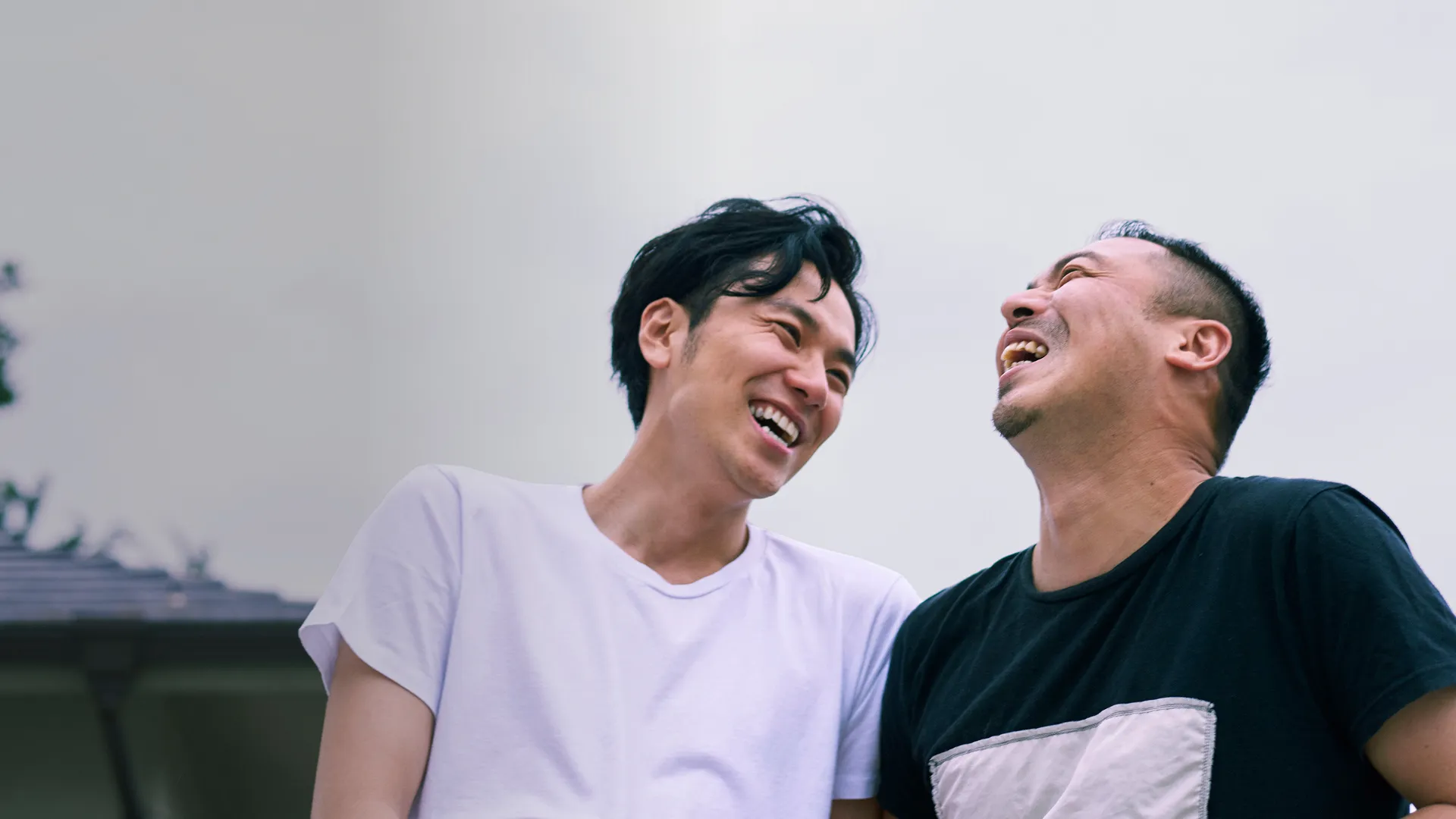 A gay Asian couple laughing together. (Generated with AI)
